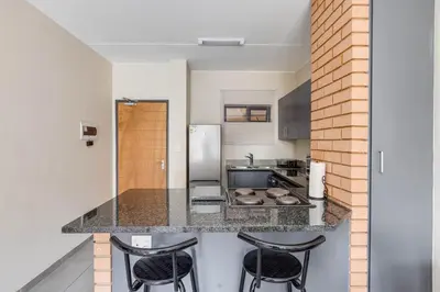 a kitchen with a counter with three stools at The Resting Nest Havilla in Midrand