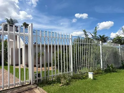 a white fence with palm trees in the background at Birch stay in Kempton Park