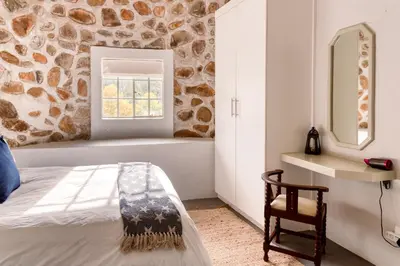a bedroom with a bed and a mirror and a chair at Trout Escape Farm in Dullstroom