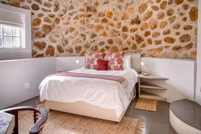 a bedroom with a bed and a stone wall at Trout Escape Farm in Dullstroom