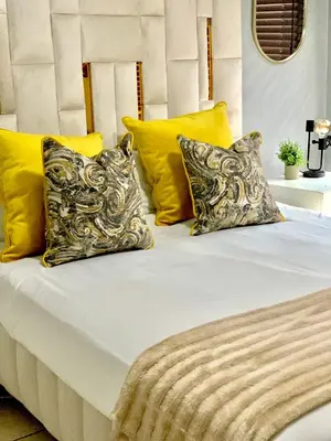 a bed with yellow and white pillows on it at The penthouse in Hartbeespoort