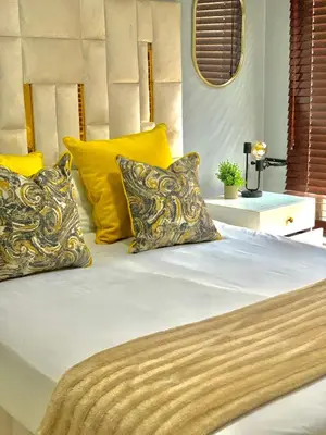 a bed with yellow and white pillows on it at The penthouse in Hartbeespoort