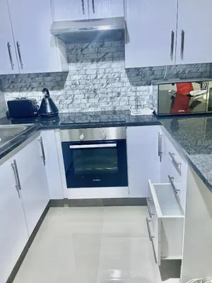 a kitchen with white cabinets and a blue oven at The penthouse in Hartbeespoort