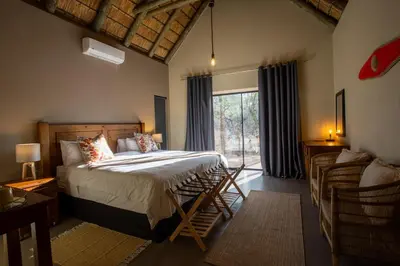 a bedroom with a bed and a large window at Vuyani Marula Lodge in Hoedspruit