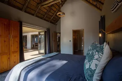 a bedroom with a bed with a blue comforter at Vuyani Marula Lodge in Hoedspruit