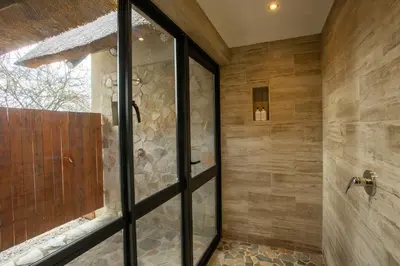 a bathroom with a shower with a glass door at Vuyani Marula Lodge in Hoedspruit