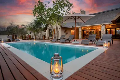 a swimming pool with a lantern next to a house at Vuyani Marula Lodge in Hoedspruit