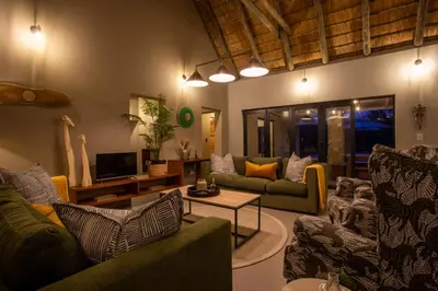 a living room with two couches and a tv at Vuyani Marula Lodge in Hoedspruit