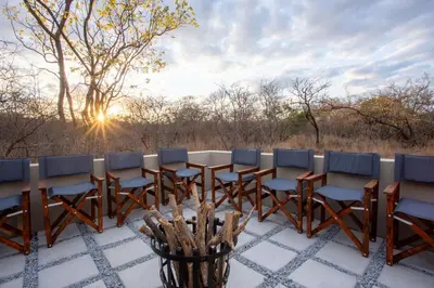 a table and chairs on a patio with the sunset at Vuyani Marula Lodge in Hoedspruit