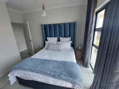 a bedroom with a large bed with a blue headboard at The Blyde Penthouse in Pretoria