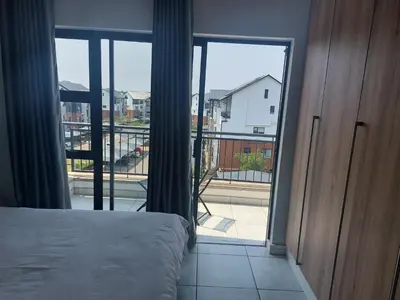 a bedroom with a bed and a view of a balcony at The Blyde Penthouse in Pretoria