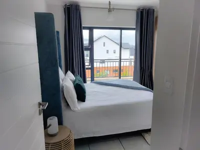 a bedroom with a bed and a large window at The Blyde Penthouse in Pretoria