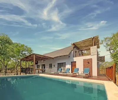 a home with a swimming pool and a house at Greater Kruger View - Luxury Bush Villa in Marloth Park