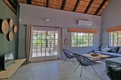a living room with a couch and a table and chairs at Greater Kruger View - Luxury Bush Villa in Marloth Park