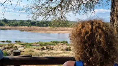 a person with curly hair looking out at a river at Greater Kruger View - Luxury Bush Villa in Marloth Park