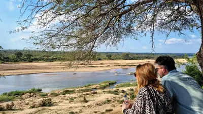 a man and a woman standing next to a river at Greater Kruger View - Luxury Bush Villa in Marloth Park