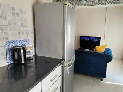 a kitchen with a refrigerator and a blue couch at Comfort place in Pretoria