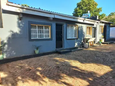 a blue and white house with a brick driveway at Comfort place in Pretoria