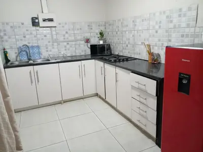 a kitchen with white cabinets and a red refrigerator at Comfort place in Pretoria