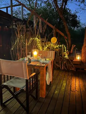 a wooden table with candles on a deck with lights at Bosveld Villa in Marloth Park