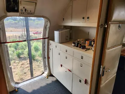 a kitchen with white cabinets and a large window at AEROTEL VIP in Hoedspruit