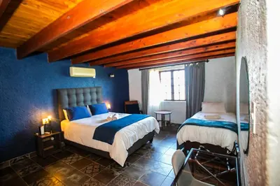 a bedroom with two beds in a room with blue walls at Koraalboom at Benlize in Hartbeespoort