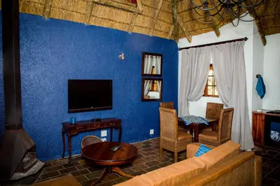 a blue living room with a couch and a tv at Koraalboom at Benlize in Hartbeespoort