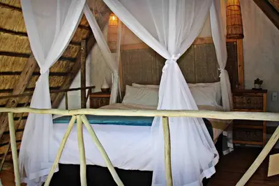 a bedroom with a canopy bed with white curtains at Hot Spring bungalow in Limpopo in Gemsbokfontein