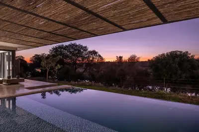 a swimming pool in a house with a sunset in the background at Maya Lodge in Hectorspruit