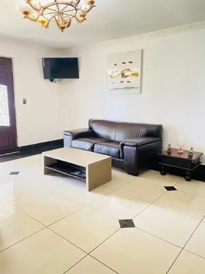 a living room with a leather couch and a coffee table at Airport Royal Guest House in Kempton Park