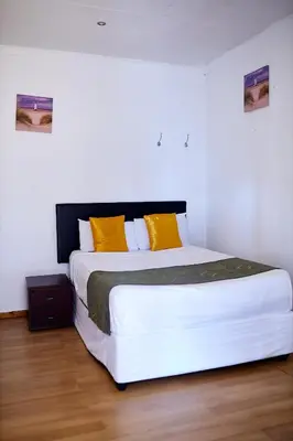 a bedroom with a large white bed with yellow pillows at Airport Royal Guest House in Kempton Park