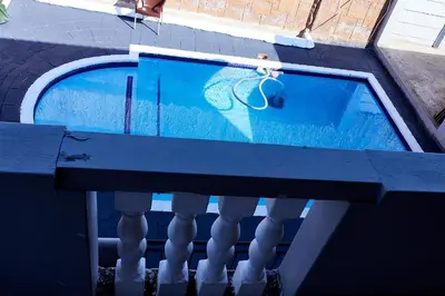 a swimming pool with a reflection of a balcony at Airport Royal Guest House in Kempton Park