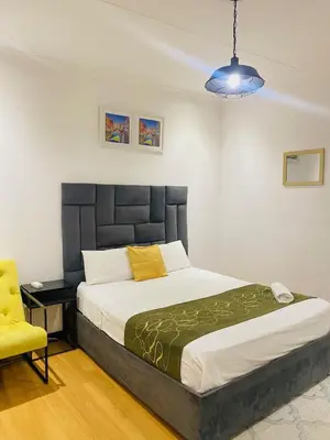 a bedroom with a large bed and a yellow chair at Airport Royal Guest House in Kempton Park