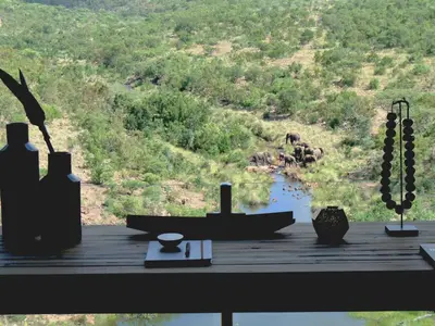 a table with vases and a view of a river at Matomo Safari Lodge in Welgevonden Game Reserve