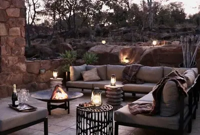a patio with a couch and tables and candles at Matomo Safari Lodge in Welgevonden Game Reserve