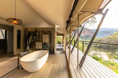a bathroom with a tub on a deck with a view at Mbizane Escarpment Retreat in Schoemanskloof