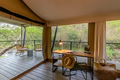 a room with a desk and chairs on a deck at Mbizane Escarpment Retreat in Schoemanskloof