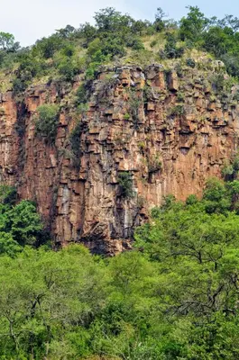 a large rocky mountain with trees in front of it at Mbizane Escarpment Retreat in Schoemanskloof