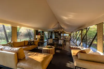 a living room with couches and tables and windows at Mbizane Escarpment Retreat in Schoemanskloof