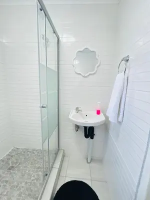 a white bathroom with a sink and a shower at Duvha Guesthouse in Graskop