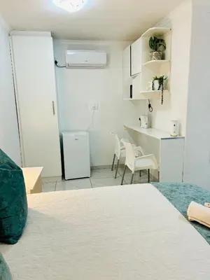 a room with a bed and chairs and a kitchen at Duvha Guesthouse in Graskop