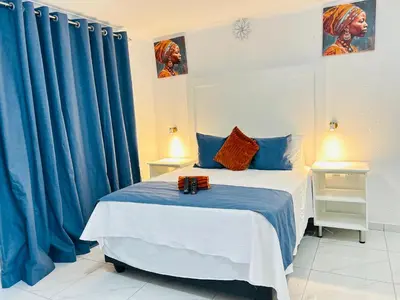 a bedroom with a bed with blue drapes at Duvha Guesthouse in Graskop