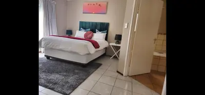 a bedroom with a bed with a red blanket on it at The Retreat, Midrand - 2bed 2bath in Midrand