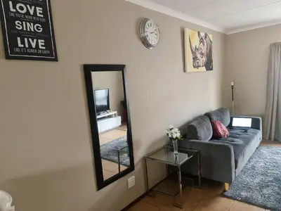 a living room with a couch and a mirror at The Retreat, Midrand - 2bed 2bath in Midrand