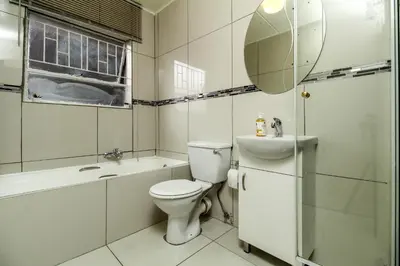 a bathroom with a toilet and a sink and a mirror at Gorgeous Diamond in Midrand
