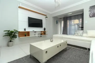 a white living room with a white couch and a tv at Gorgeous Diamond in Midrand