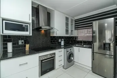 a kitchen with white cabinets and a washer and dryer at Gorgeous Diamond in Midrand