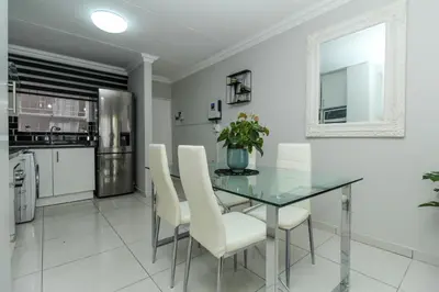a dining room with a glass table and white chairs at Gorgeous Diamond in Midrand