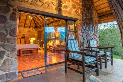 a room with two rocking chairs and a bedroom at Iketla Lodge in Ohrigstad