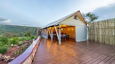 a house with a deck with a table on it at Iketla Lodge in Ohrigstad
